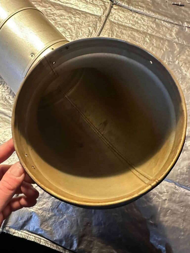 Montør holder et ventilationsrør med aflejret snavs før rensning