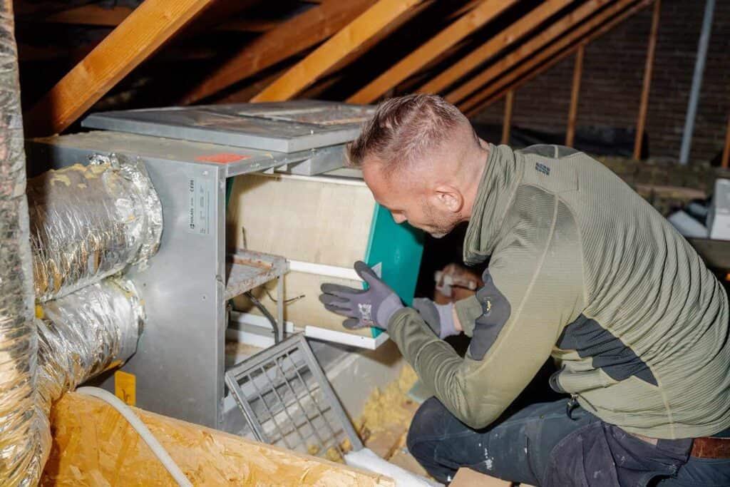 Montør servicerer et ventilationsaggregat på loftet