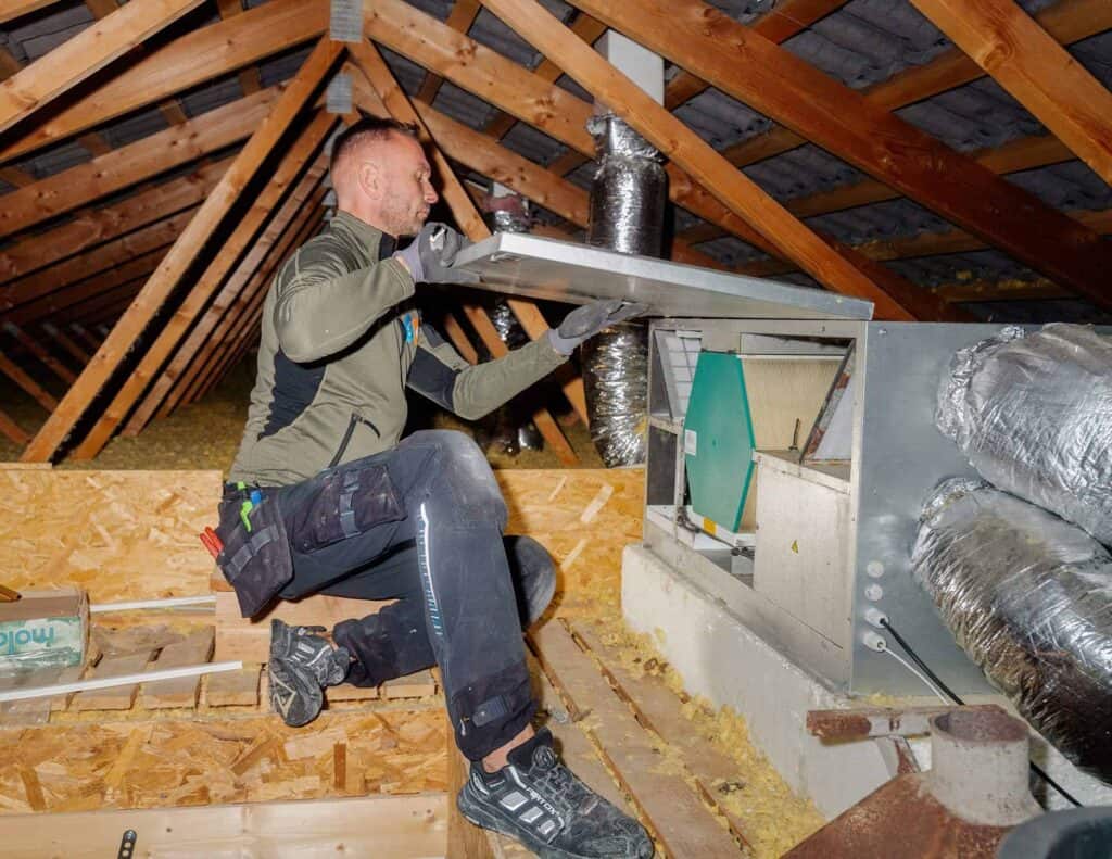 Montør monterer ventilationskanaler på et uudnyttet loft