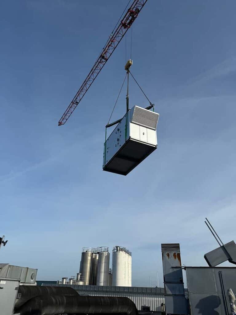 Tårnkran løfter et ventilationsaggregat ind over en fabrik
