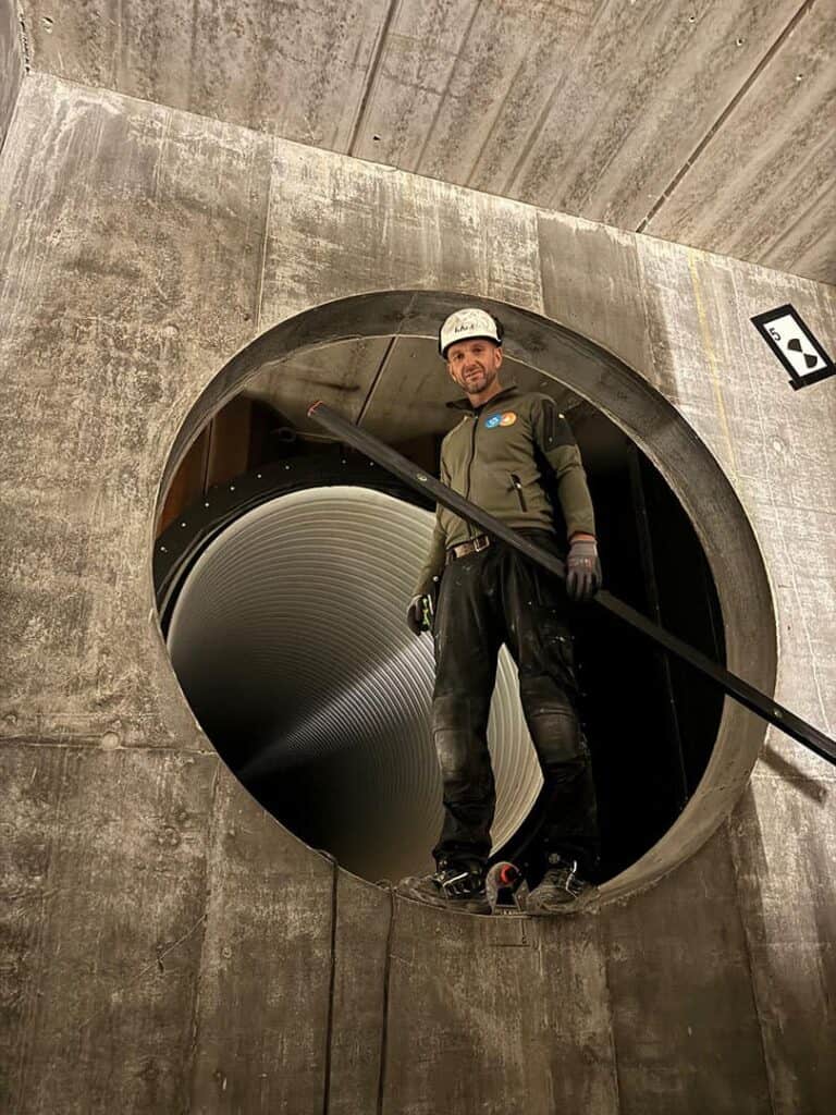 Montør i et stort betonrør under montage af ventilationskanal